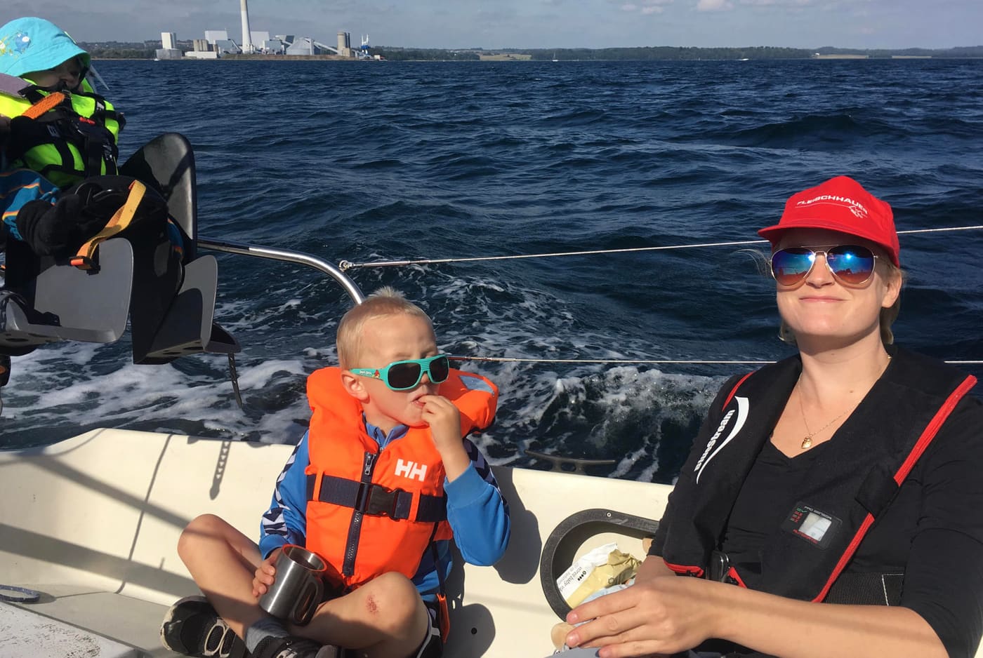 Familie på sejltur, hvor barnet har redningsvest på i cockpittet